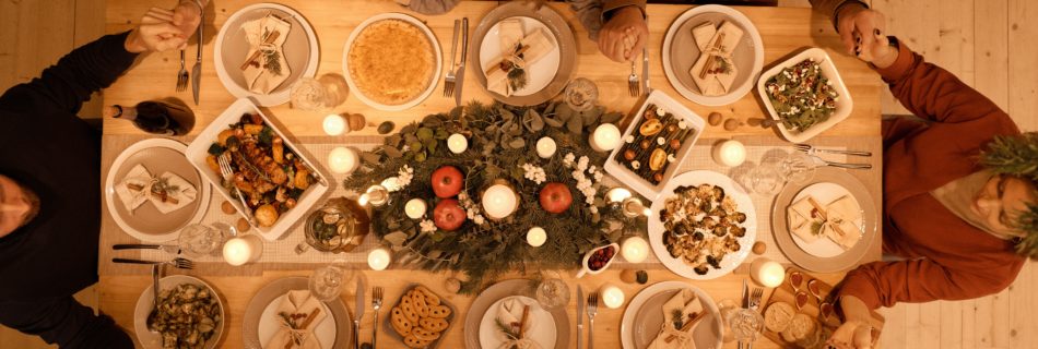 Family holding hands around holiday dinner table